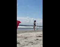Woman black onesie jumping jacks beach red flag