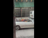 Guy sitting in convertible with three mannequins wearing masks