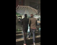 Raining guy black jacket black hat carrying huge table umbrella striped