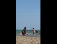 Red bikini girl kneels beach shore windy 