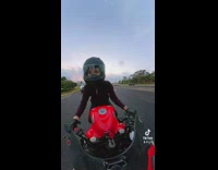 Woman riding red motorcycle on streets pov waving at cars