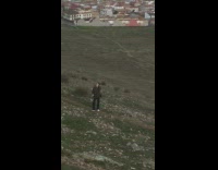 Woman takes picture in field, man narrates funny commentary