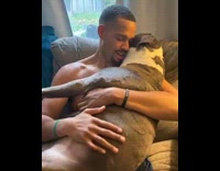 Shirtless guy holds pets large dog sings