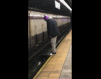 Man hangs his toes over the edge of subway train platform