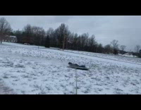 Car pulls guy on black plastic snow 