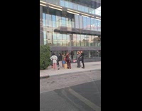 People in suits films on the sidewalk