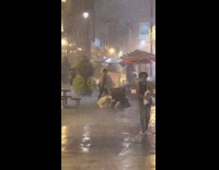 Woman does yoga leg lift stretch in the pouring rain next to umbrellas