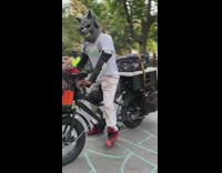 Man with grey wolf head on bike in park