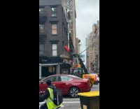 Two guys ride excavator bucket on road