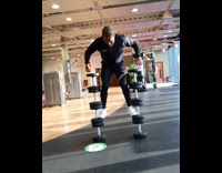 Guy jumps up stack of dumbbells gym 