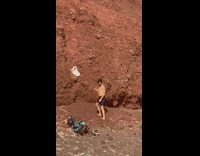 Man takes picture of white tank top on the beach rock