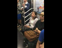 Woman green pants sits on small black stool on subway train