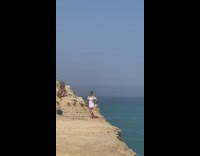 White dress girl poses cliff by ocean 