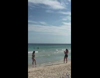 Woman pink bikini takes picture of friend at the beach