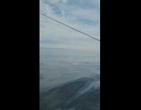 Boat pass by calm ocean water cloudy