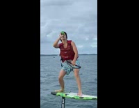 Guy drinks while balancing on board attached to boat 