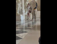 Lady in White Attire Poses Besides Sculptures