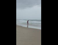 Woman dance arms wave continuously beach overcast