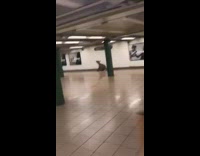 Rat costume guy crouches subway station wall 
