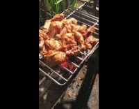 Guy cooks chicken over open fire coal