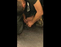 Man gray shirt bends over and clips toenails on subway train