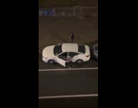 Two women sing loudly beside white car