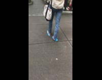 Woman wears blue flimsy sandals on sidewalk  after pedicure