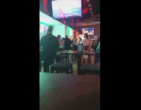 a girl poses at a bar wearing a white sweater under tvs