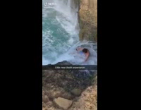 Ocean wave knocks over blue shorts guy