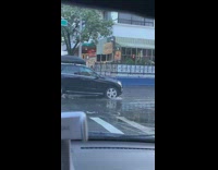 Cars drive down flooded street during daytime 