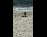 Woman in black bikini fixes her hair at the beach