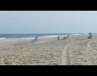 Pink bikini girl squats beach sand chair 
