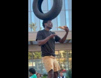Man balance tire on head eat pizza