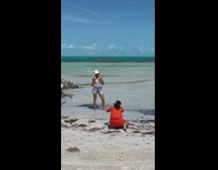 Woman drinks juice conch shell phone beach