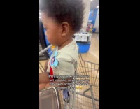 Boy in cart stares at kid crying