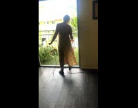 Orange dress mom vacuums fake grass balcony