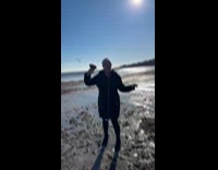 Woman holding clam with seagull approaching