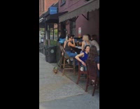 Woman outside bar sits beside the dumpster