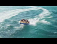 4 people sit on a float being pulled by boat 