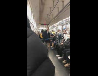 Four guys dance crowded subway metal pole