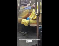 Guy Sits in Yellow Suit and Face Shield 