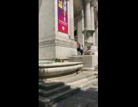 Two homeless men take a bath in fountain in front of New York Public Library