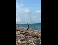Guy black shorts cap kneel beach selfie