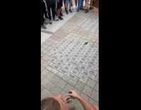 Two people reveal the tiles on the floor to a crowd of people