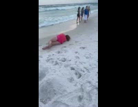Woman pink shirt stumble down the beach