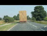 Hay on truck blow towards car wind 