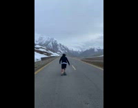 Skateboarder rides down road with mountains 
