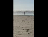 Woman in bikini coat poses with tripod at the beach