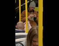 Brown jacket guy eats uncooked sausage subway