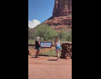 Woman in brown dress stands on top of the pile of rocks